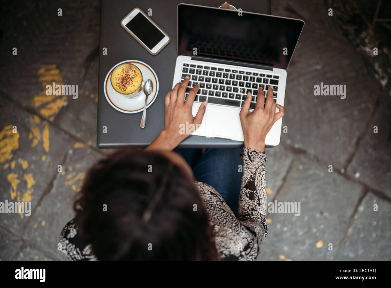 Top view of young woman using laptop at a pavement cafe Stock Photo - Alamy
