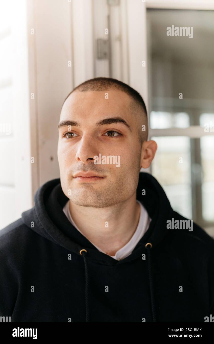 Portrait of pensive young man with shaved head looking at distance Stock Photo