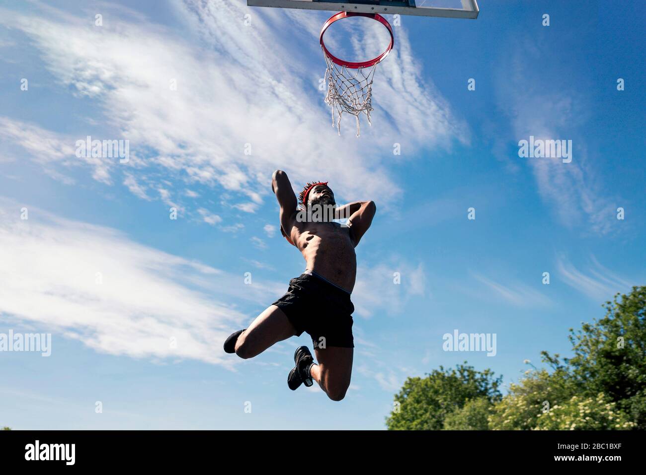 Man playing basketball, dunking Stock Photo