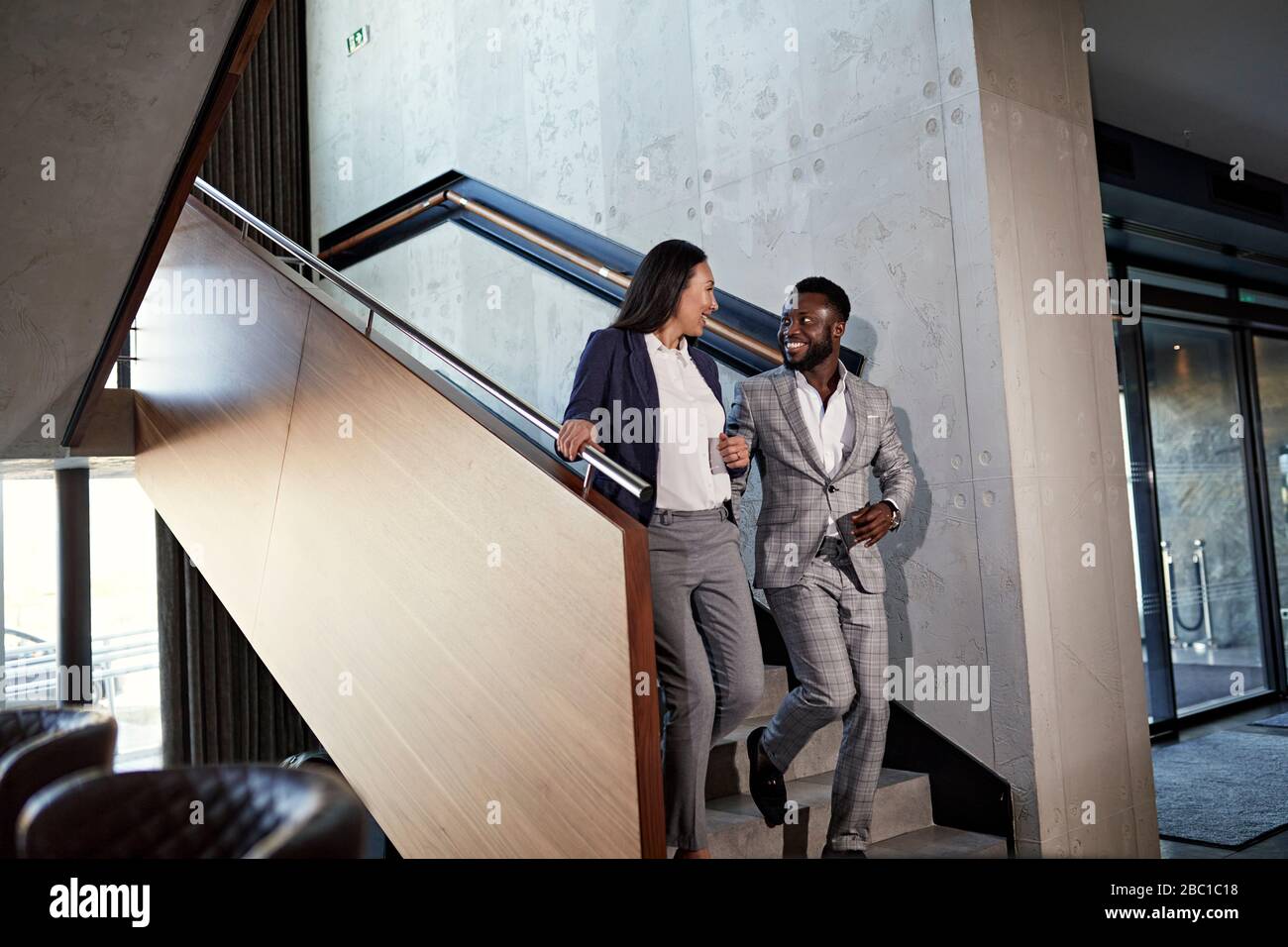 Businessman and businesswoman walking down staircase Stock Photo - Alamy