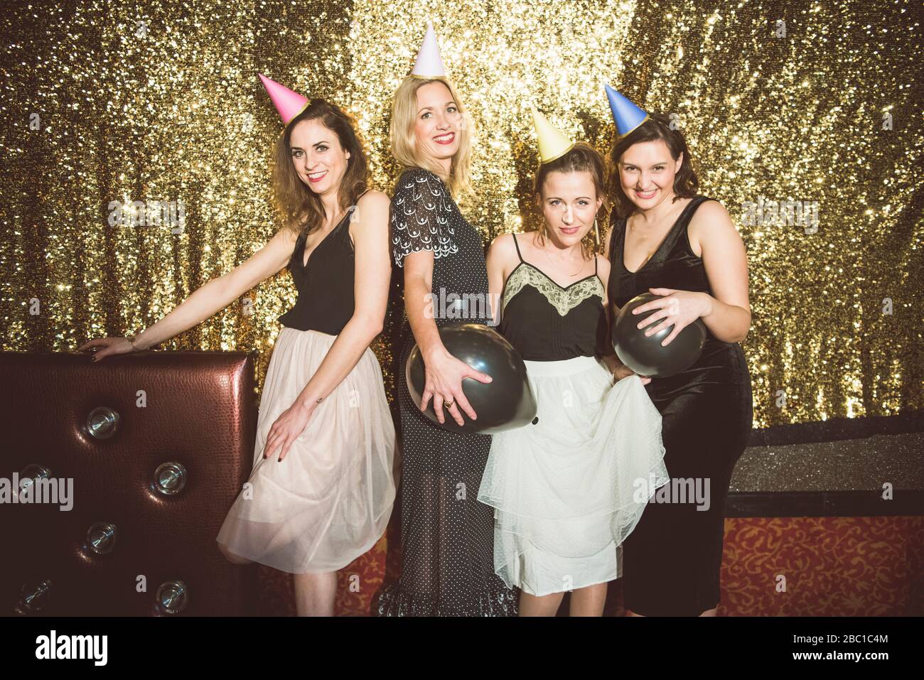 Portrait of four happy women wearing party hats in a club Stock Photo