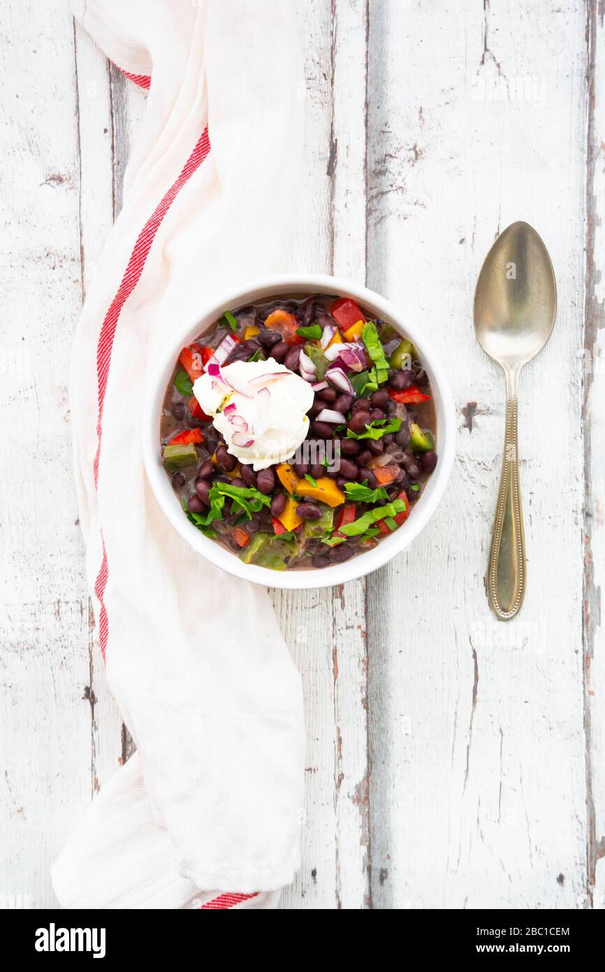 Bowl of black bean soup with bell pepper, cilantro, sour cream and red onions Stock Photo
