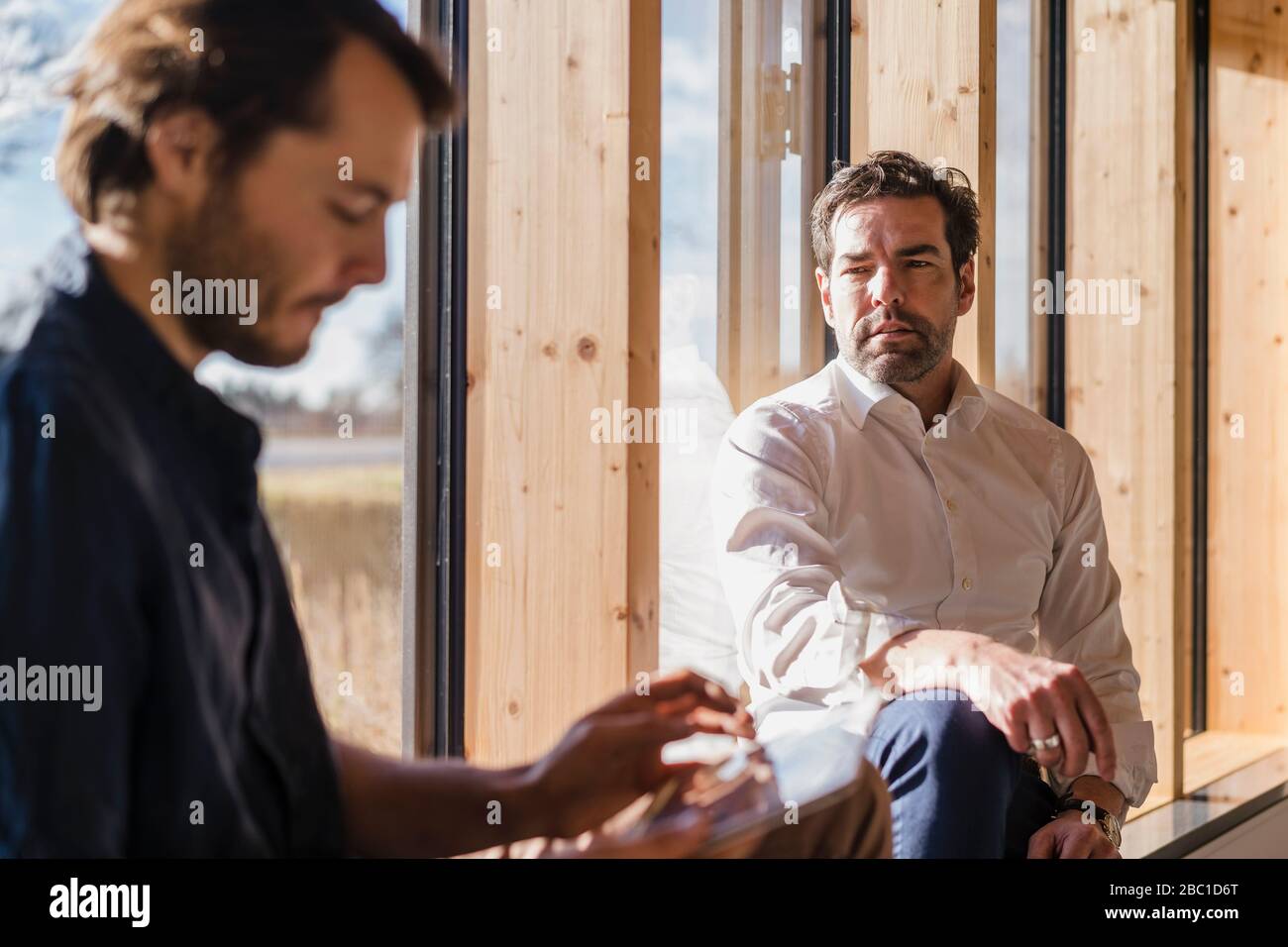 Two businessmen talking at the window in office Stock Photo - Alamy