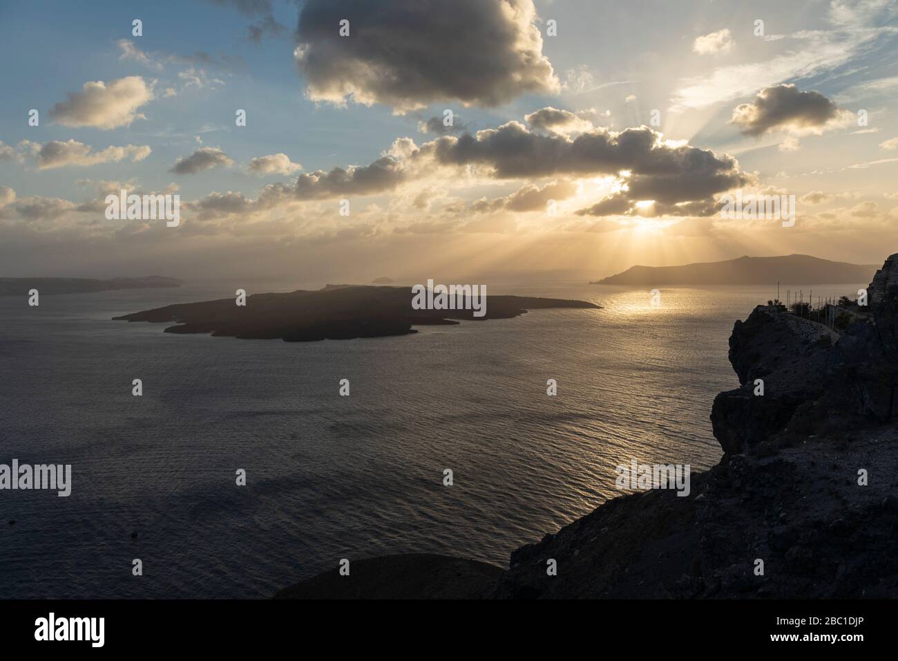 Sun rays as the sun sets over Santorini caldera and Nea Stock Photo