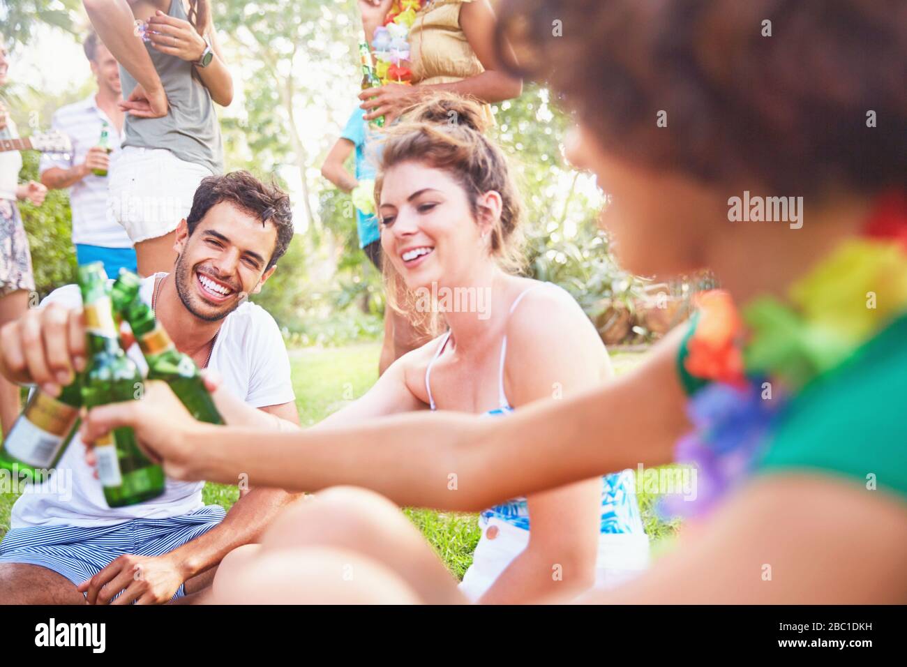 Young friends hanging out, toasting beer bottles in summer park Stock Photo