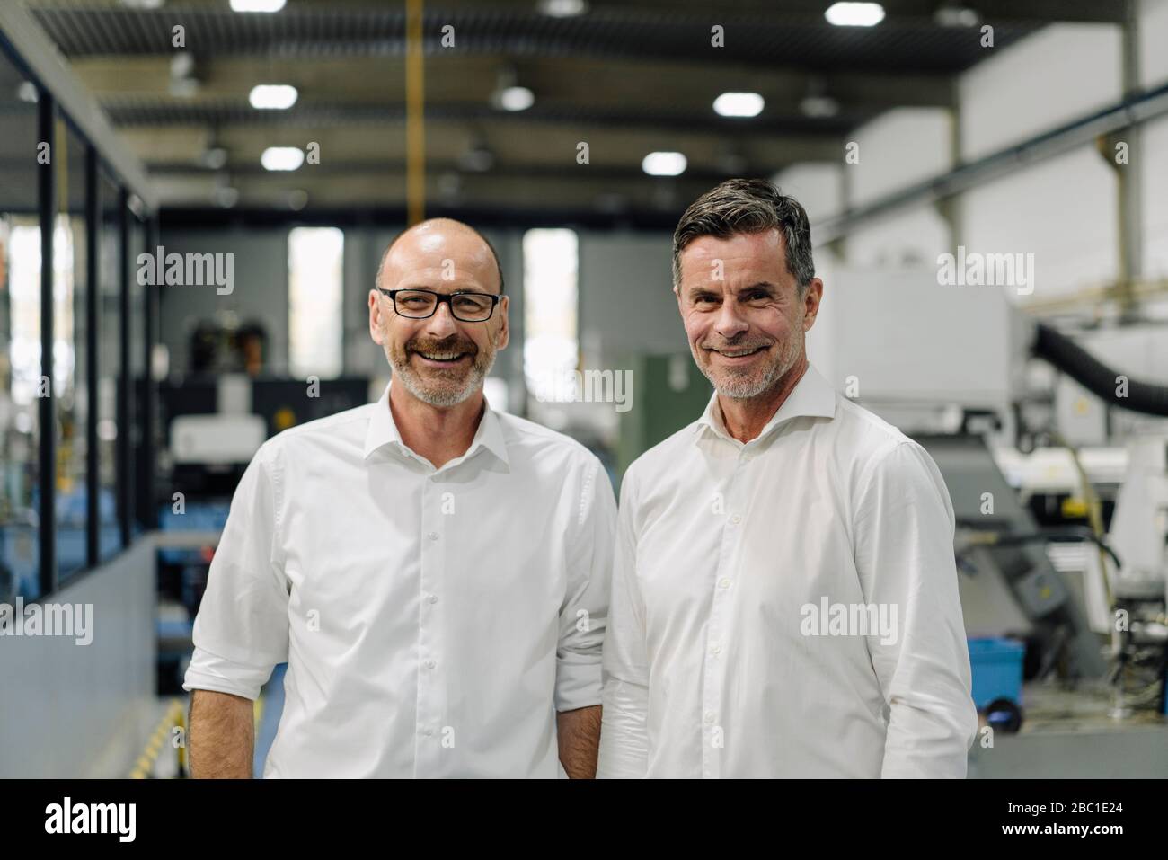 Portrait of two smiling businessmen in a factory Stock Photo - Alamy