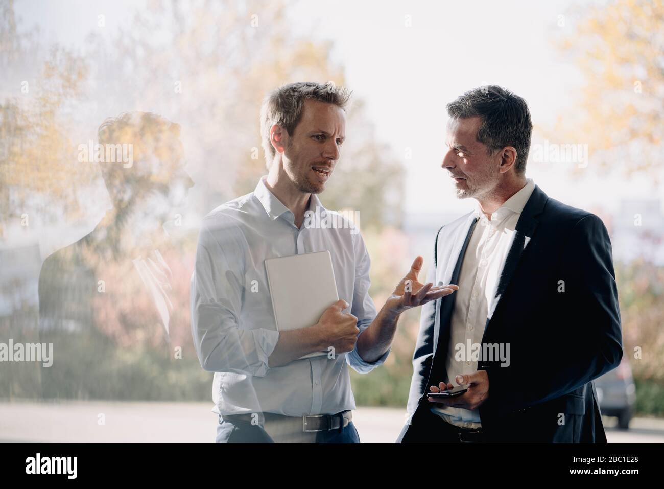 Two businessmen talking at the window Stock Photo - Alamy