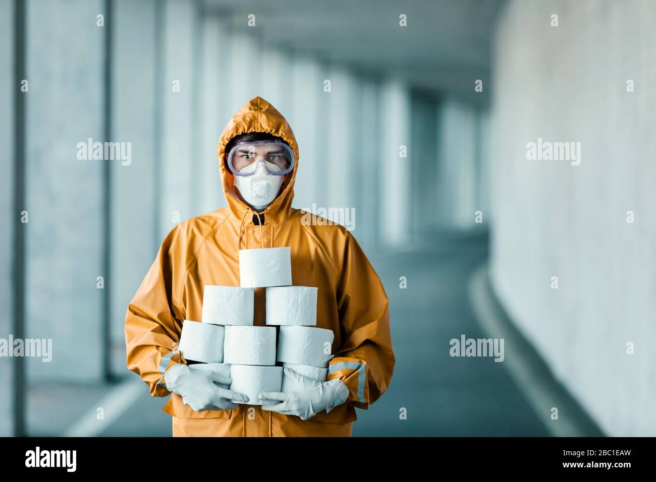 Portrait of man wearing protective clothing holding toilet rolls Stock Photo