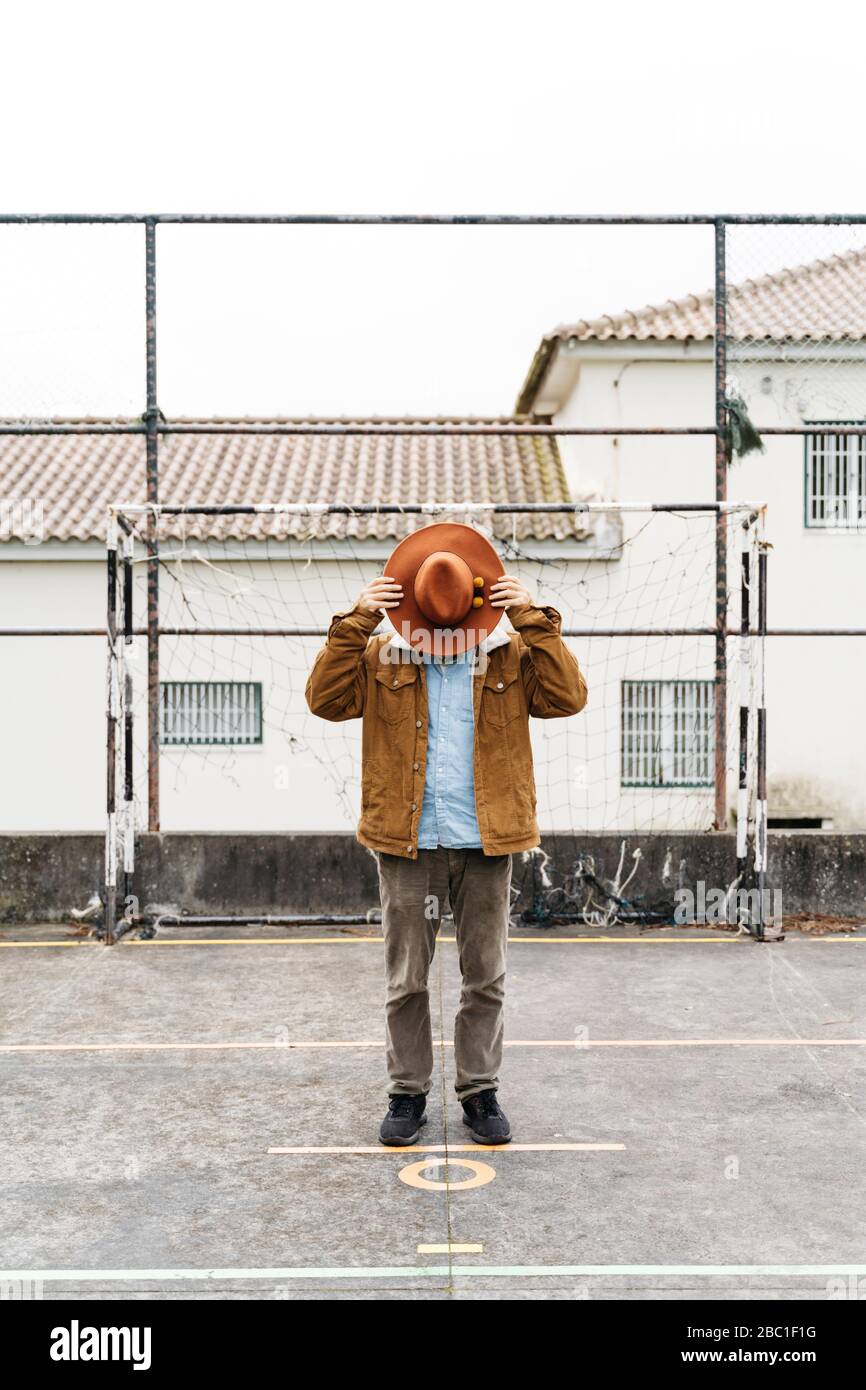 Man standing on sports field covering his face with a hat Stock Photo