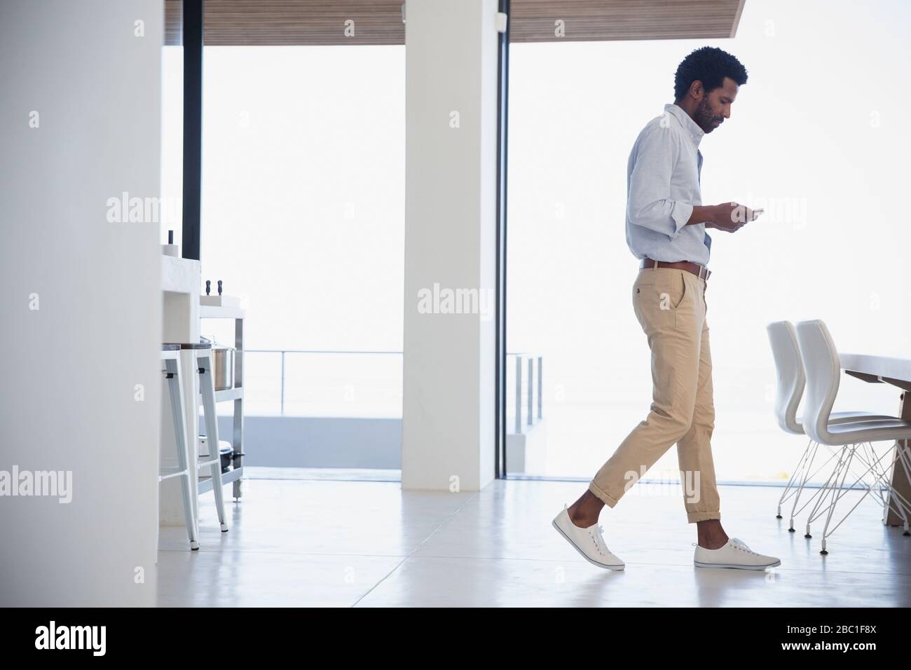 Businessman texting, walking in dining room Stock Photo