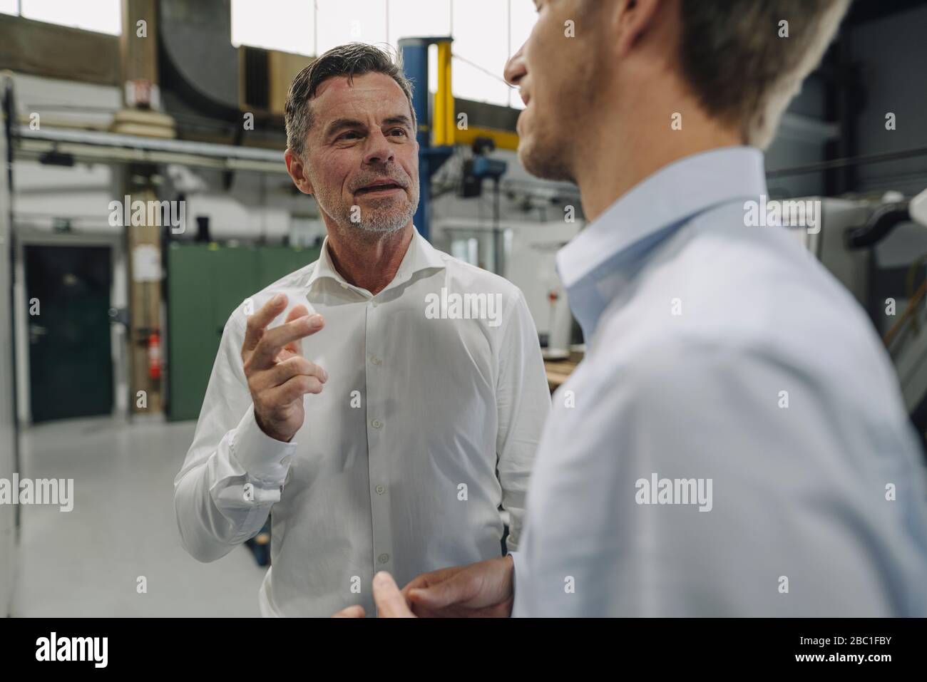 Two men talking in a factory Stock Photo - Alamy