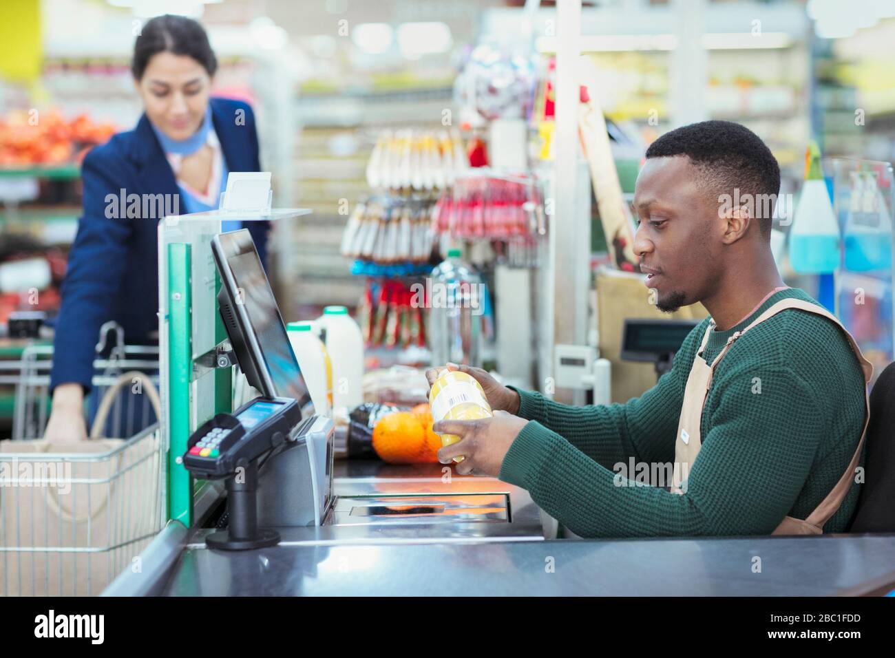 Cashier ringing up customer at supermarket checkout Stock Photo