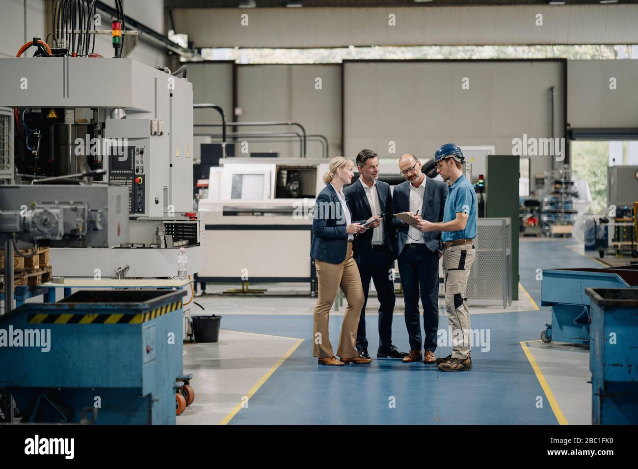 Business people and worker talking in a factory Stock Photo