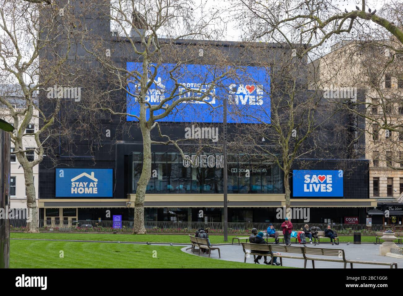 A nearly deserted Leicester Square in Central London during the corona virus outbreak. The Odeon Cinema has signs warning people to Save Lives etc. Stock Photo