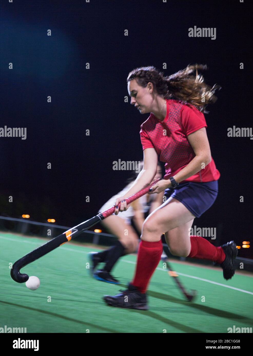 Female hockey player hitting ball hires stock photography and images