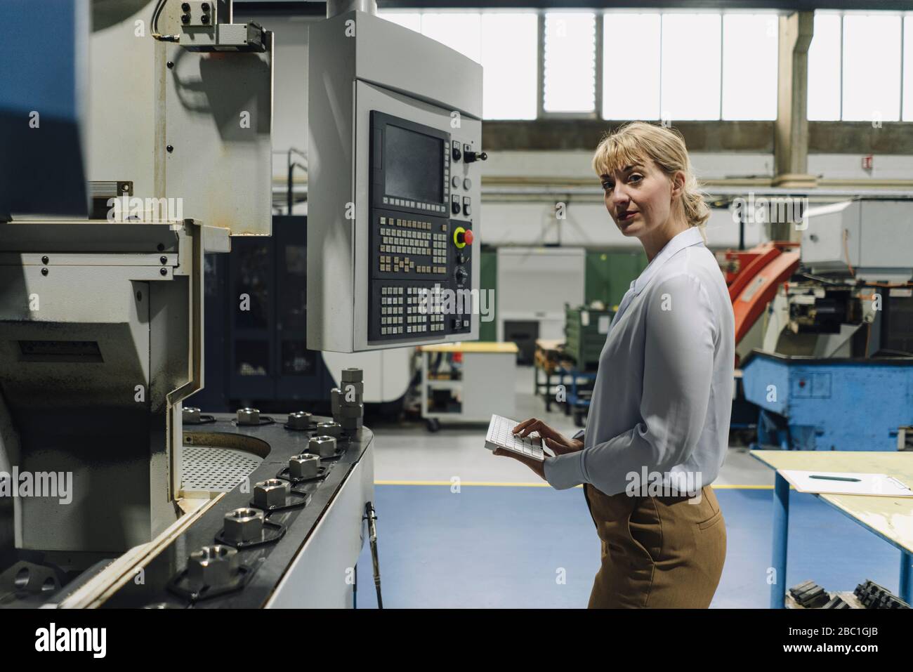Portrait of a confident businesswoman using wireless keyboard in a factory Stock Photo