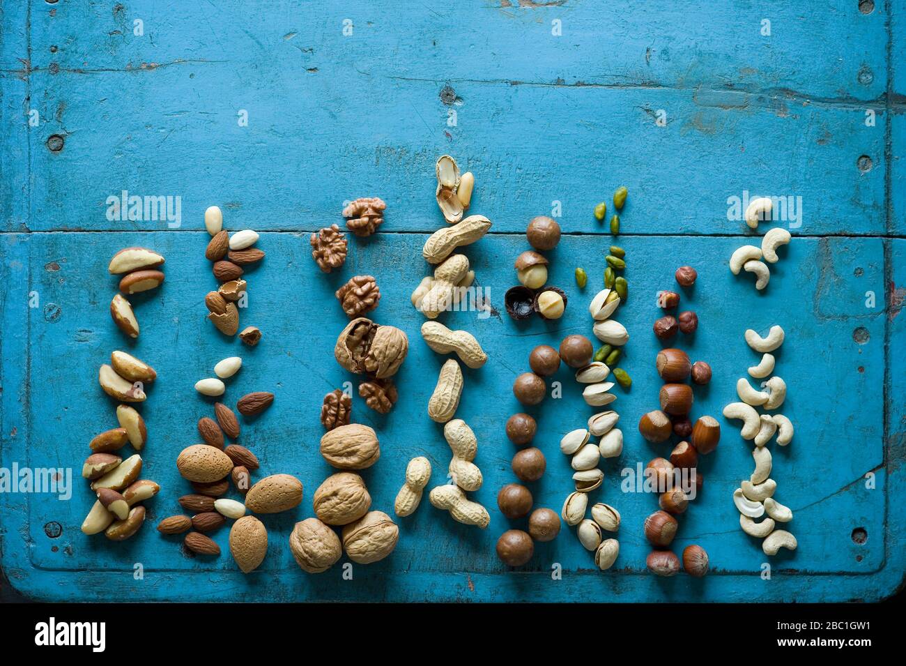 Overhead view of various nuts on blue rustic table Stock Photo