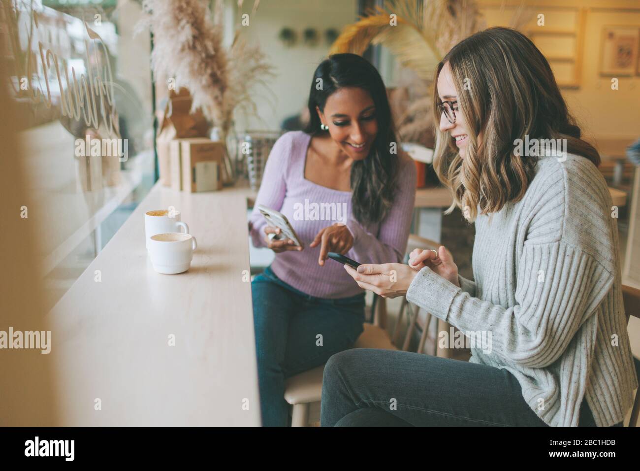 Two women using smartphones in a cafe Stock Photo