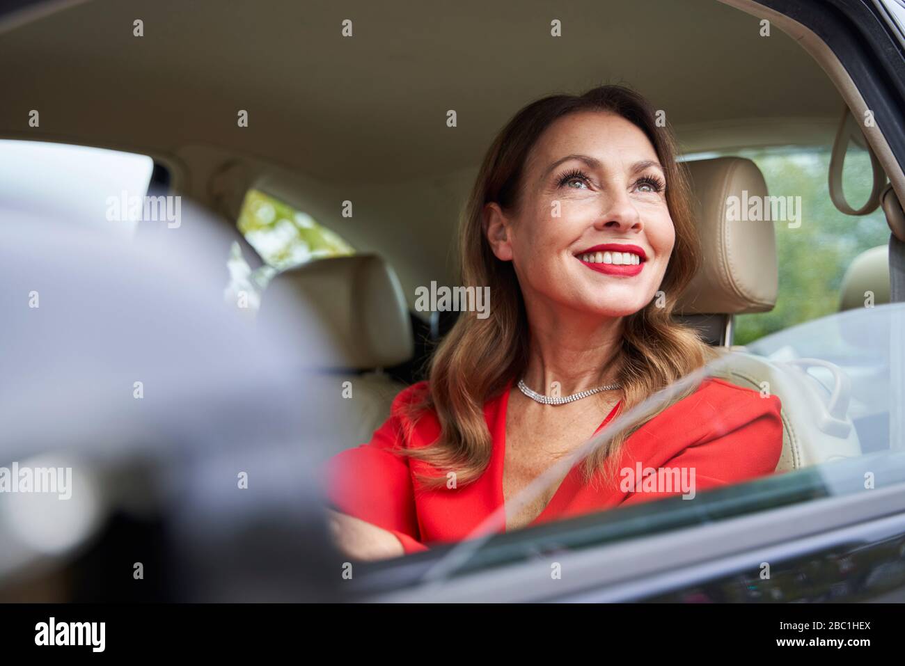 Portrait of smiling mature woman looking out of car window Stock Photo ...