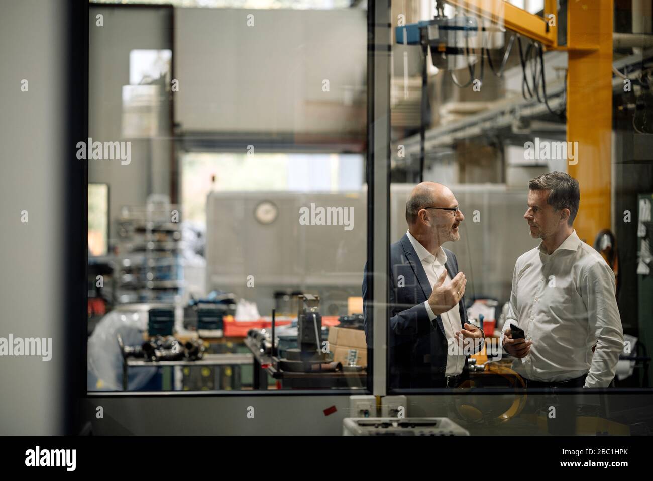 Two businessmen talking in a factory Stock Photo - Alamy