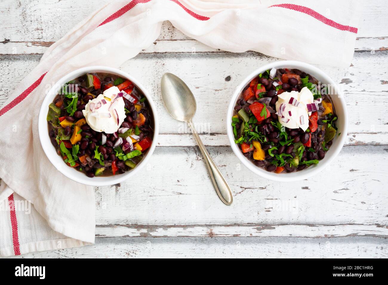 Two bowls of black bean soup with bell pepper, cilantro, sour cream and red onions Stock Photo