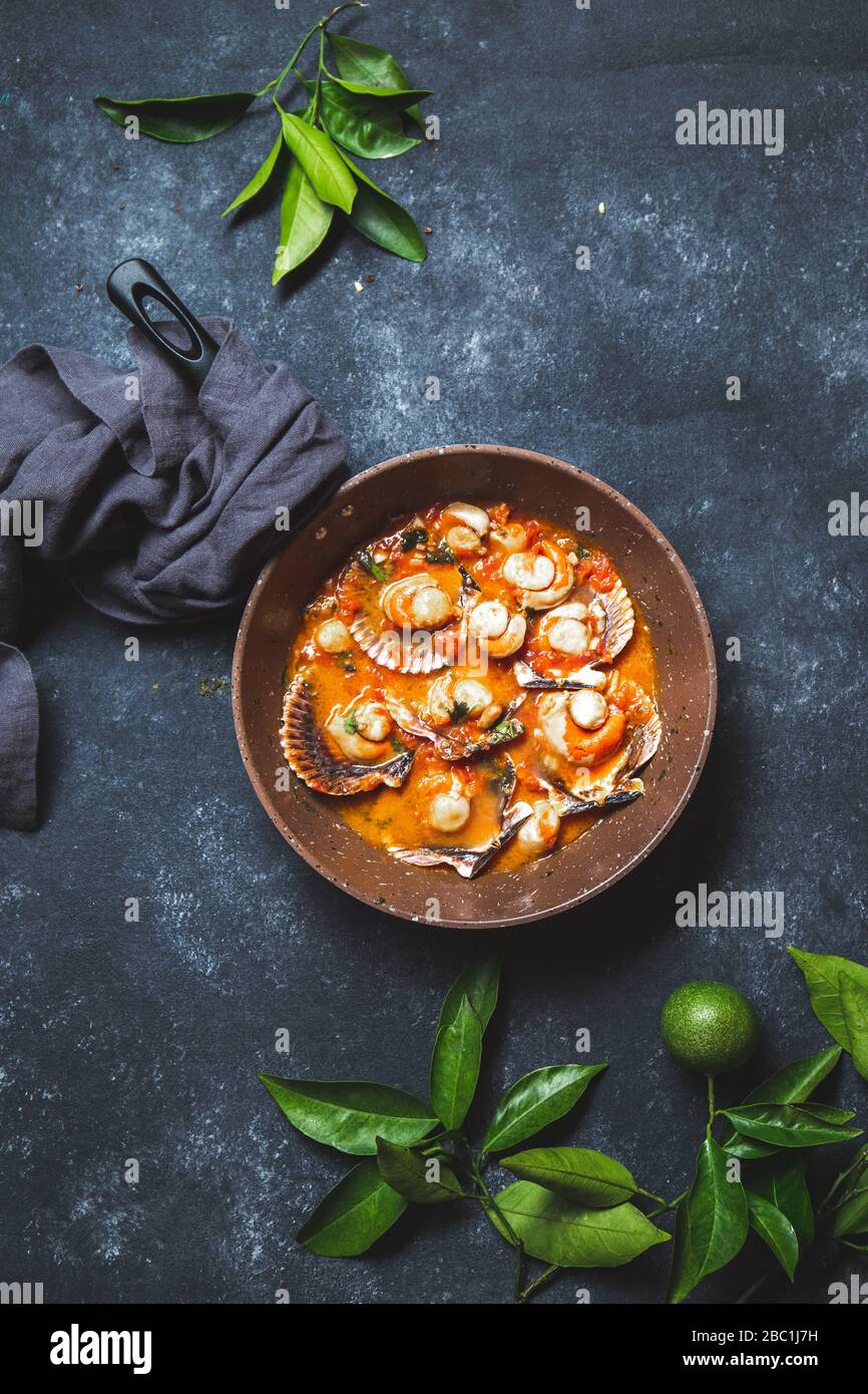 Scallops on tomato and white wine sauce with lemon, cilantro in pan on