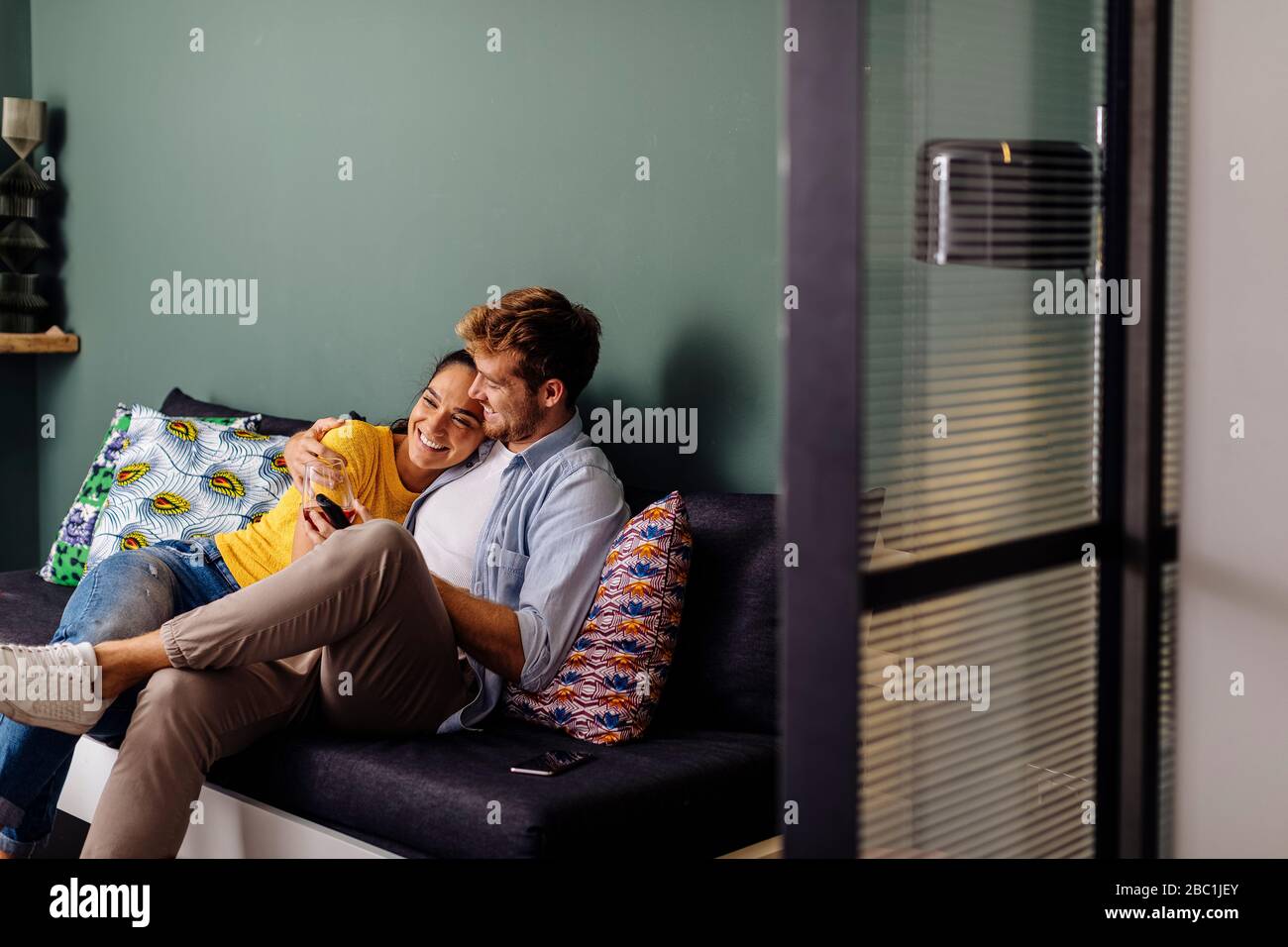 Happy affectionate young couple sitting on the couch at home Stock Photo