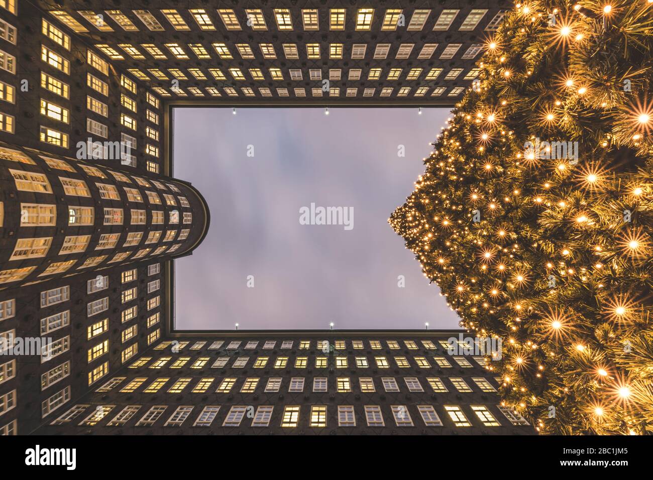 Germany, Hamburg, Directly below view of glowing Christmas tree and exterior of Sprinkenhof building Stock Photo