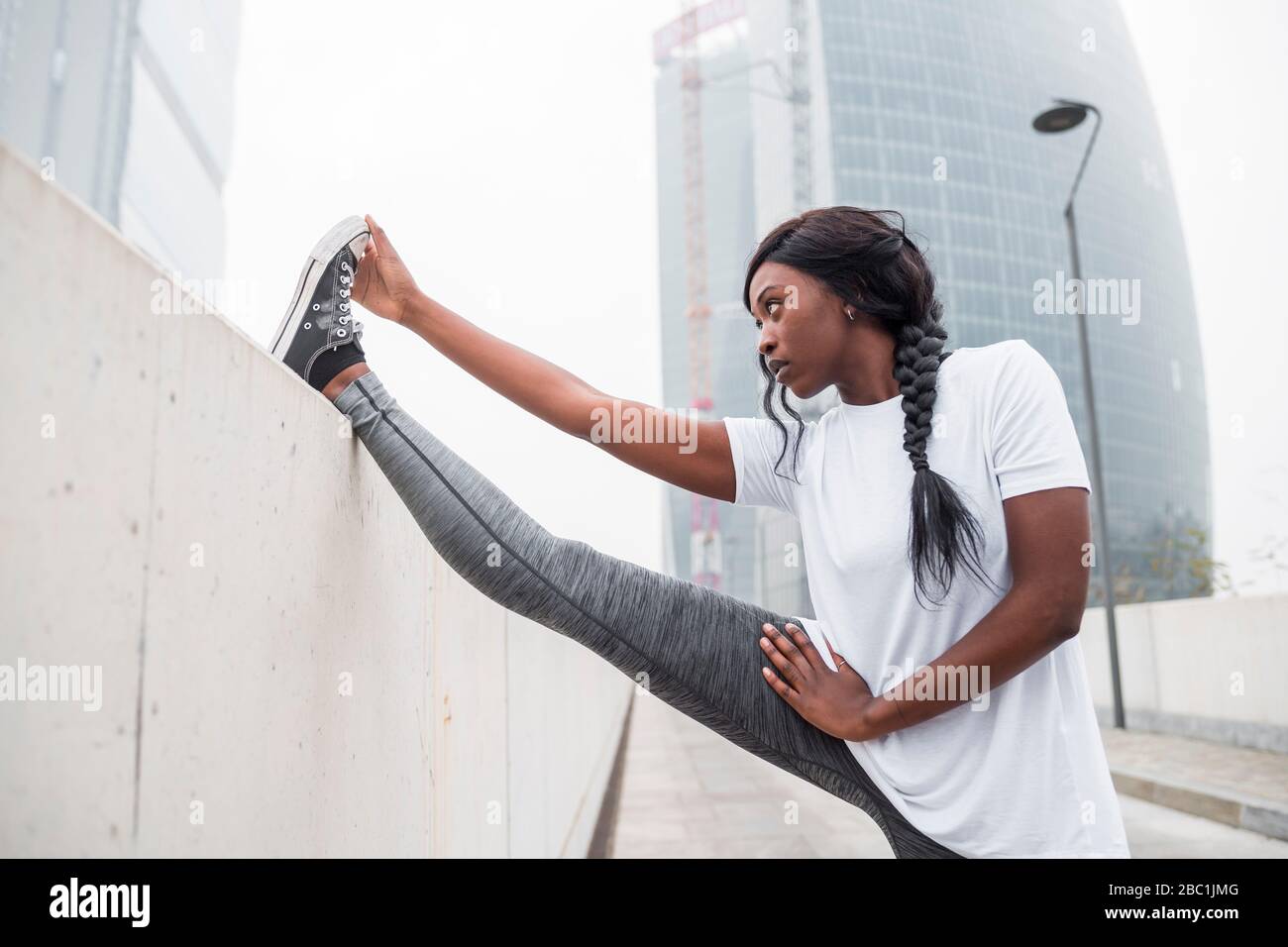 Sportive young woman stretching in the city Stock Photo