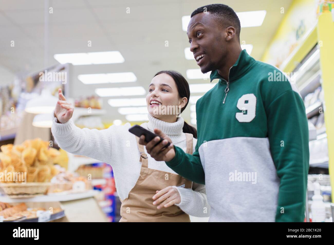 Female grocer helping customer in supermarket Stock Photo - Alamy