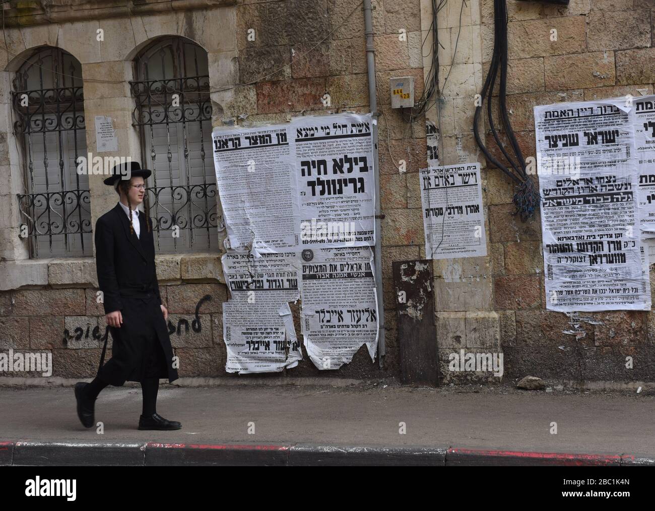 Jerusalem, Israel. 02nd Apr, 2020. An Ultra-Orthodox Jew walks past posters warning about the coronavirus, in the Mea Shearim neighborhood in Jerusalem, on Thursday, April. 2, 2020. The cases of coronavirus has jumped in Israeli Ultra-Orthodox cities, amid growing concerns of a major outbreak of COVID-19 in the religious communities. Photo by Debbie Hill/UPI Credit: UPI/Alamy Live News Stock Photo