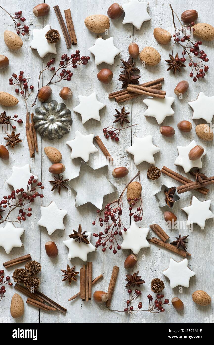 Star shaped cookies, cinnamon sticks, star anise, cookie cutters, pine cones, rose hips, almonds and hazelnuts Stock Photo