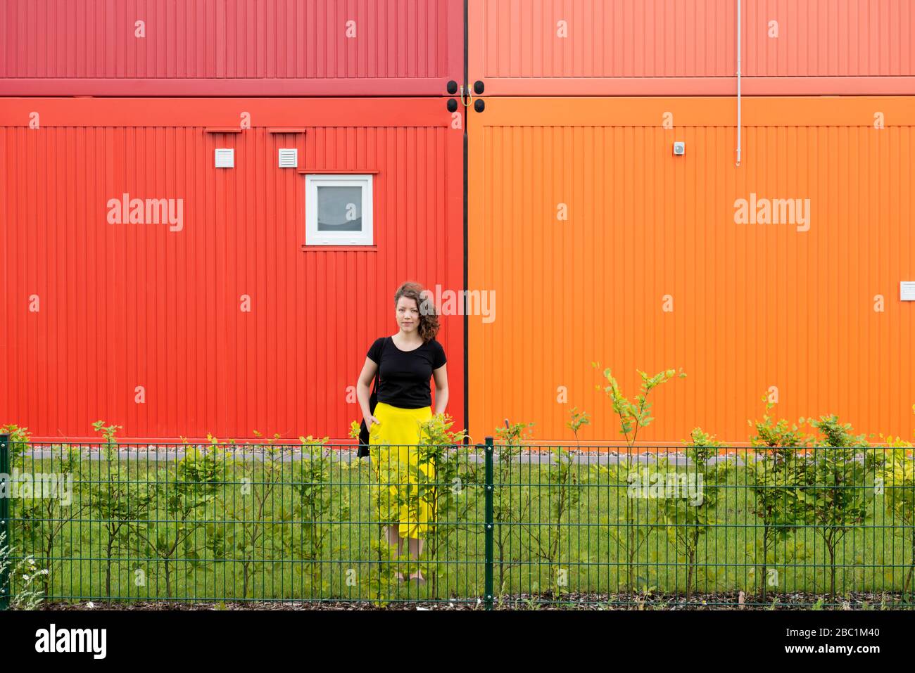 Portrait of woman standing in front of a colorful two-story container building Stock Photo