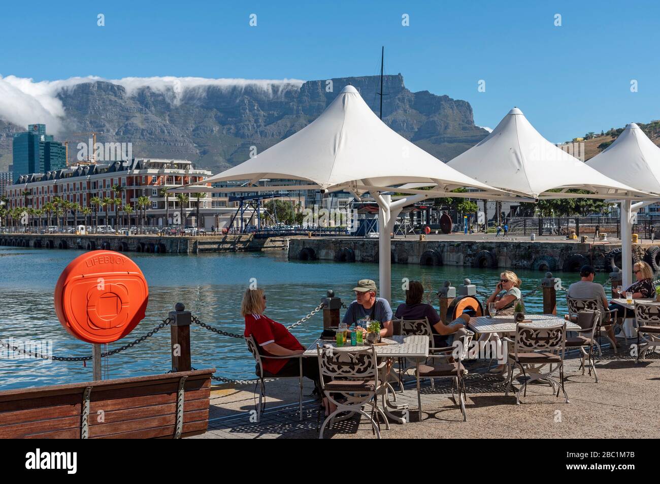 Cape Town, South Africa. 2019. Landcape view of the waterfront with tourists eating and drinking and cloud creeping over the summit of Table Mountain. Stock Photo