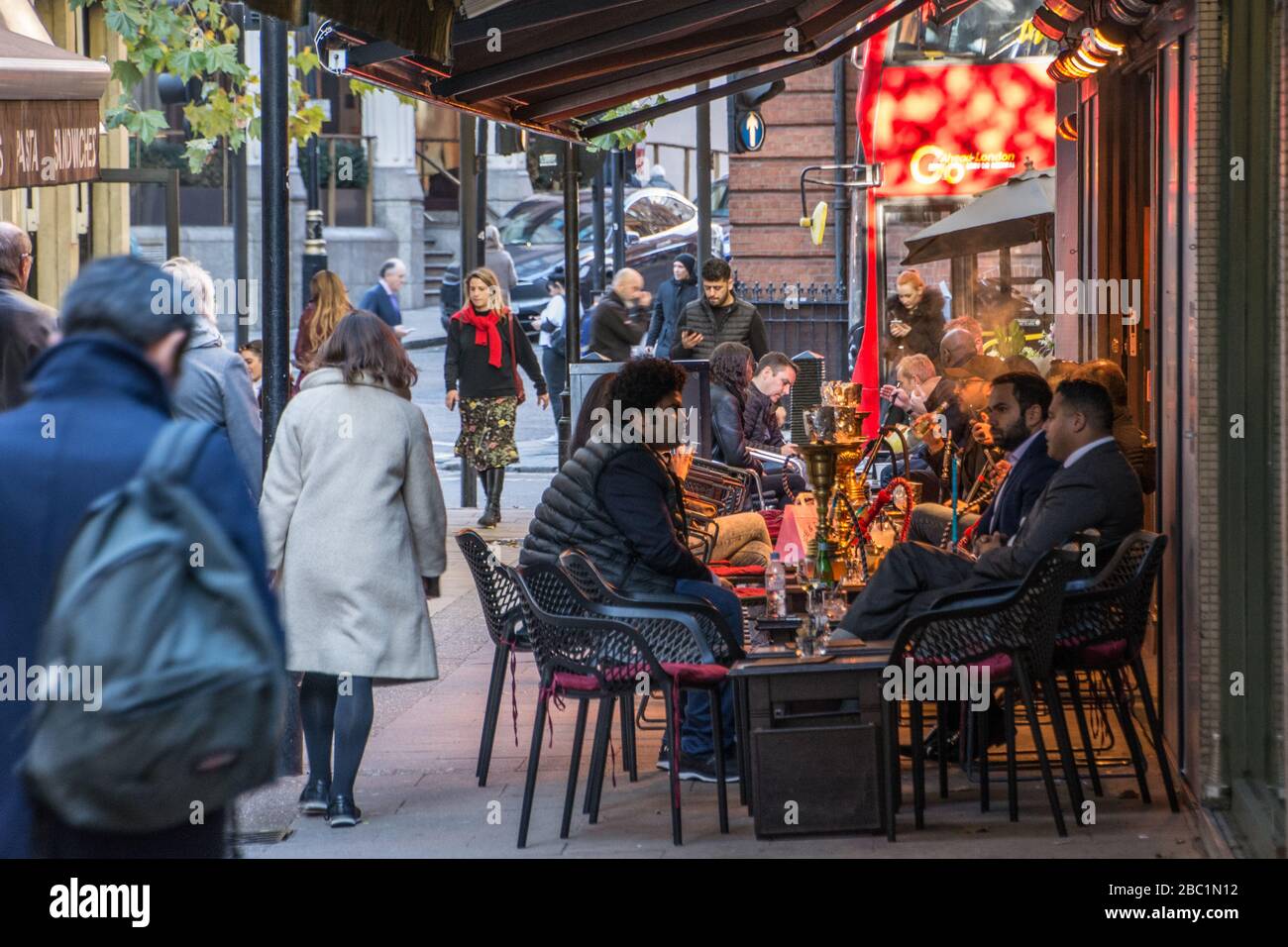 Business people smoking shisha outside lounge bar in Mayfair London