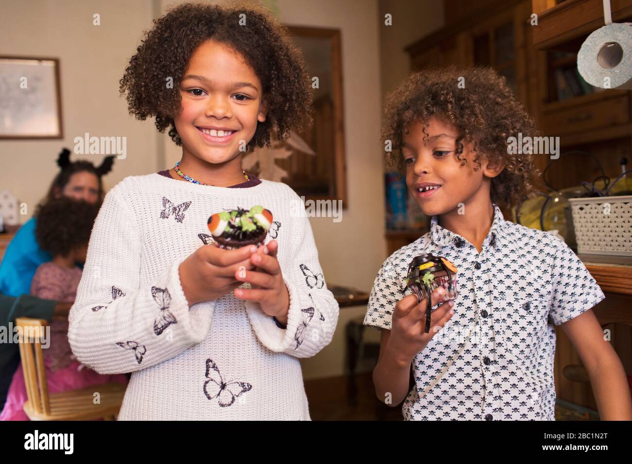 Portrait happy brother and sister with decorated Halloween cupcakes Stock Photo
