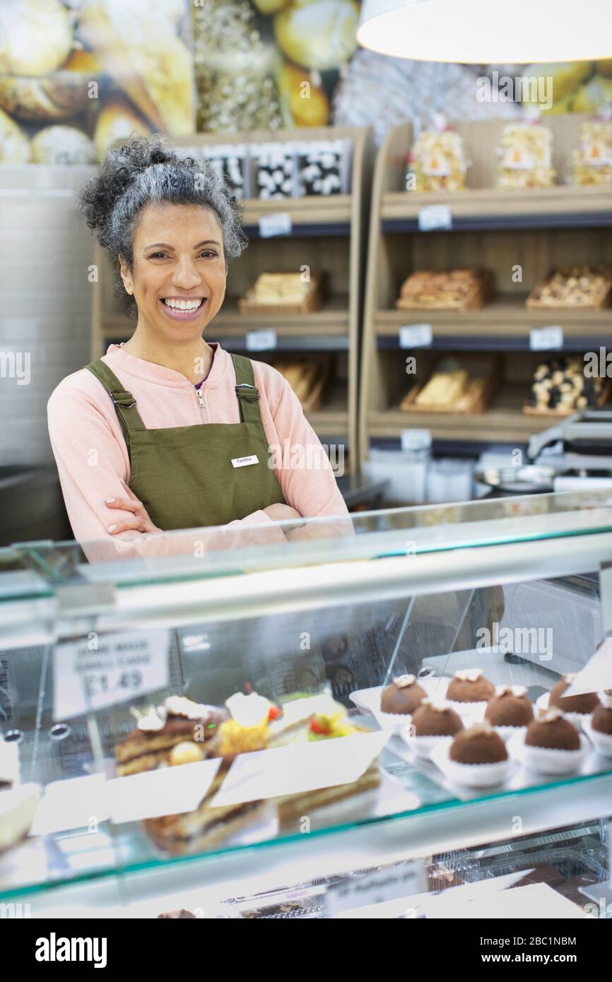Portrait smiling, confident female worker behind display case in supermarket Stock Photo