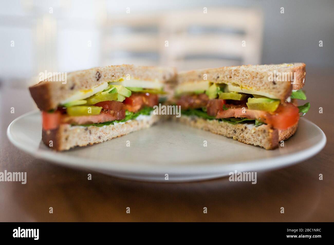 A vegetarian sandwich with avocado and tomato on whole wheat bread ready for a healthy, delicious lunch. Stock Photo