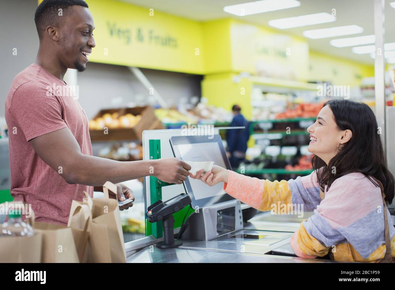 Cashier giving receipt to customer at supermarket checkout Stock Photo