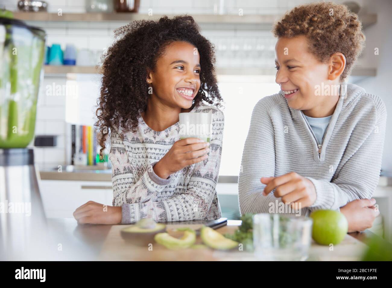 Smiling brother and sister drinking healthy green smoothie in kitchen Stock Photo