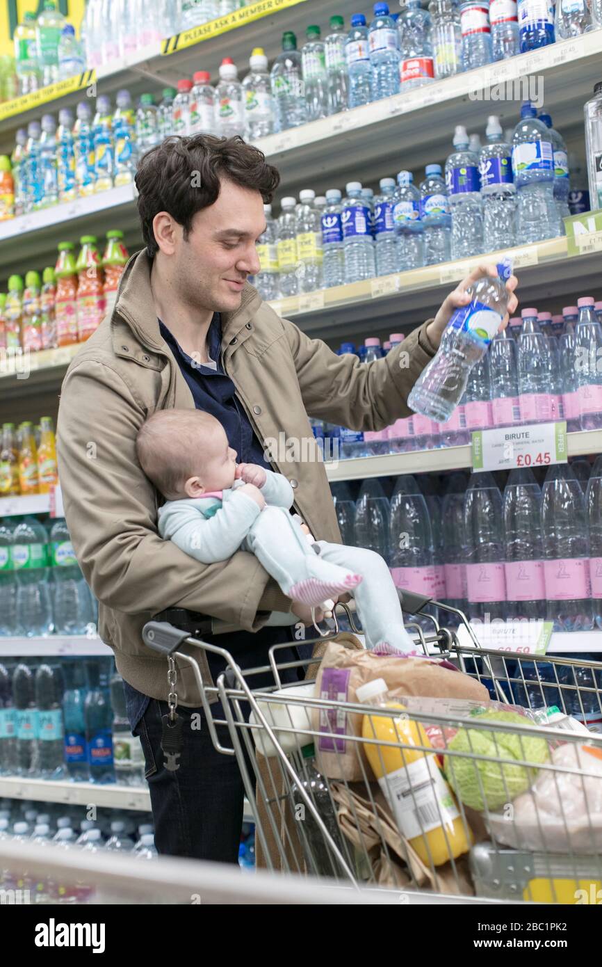 Father with baby daughter grocery shopping in supermarket Stock Photo