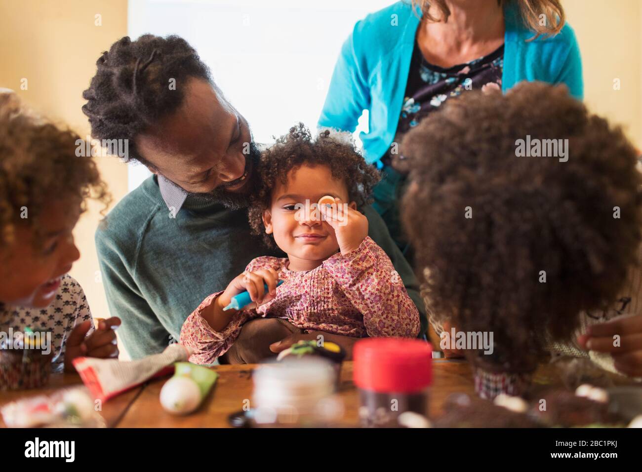Family decorating cupcakes at table Stock Photo