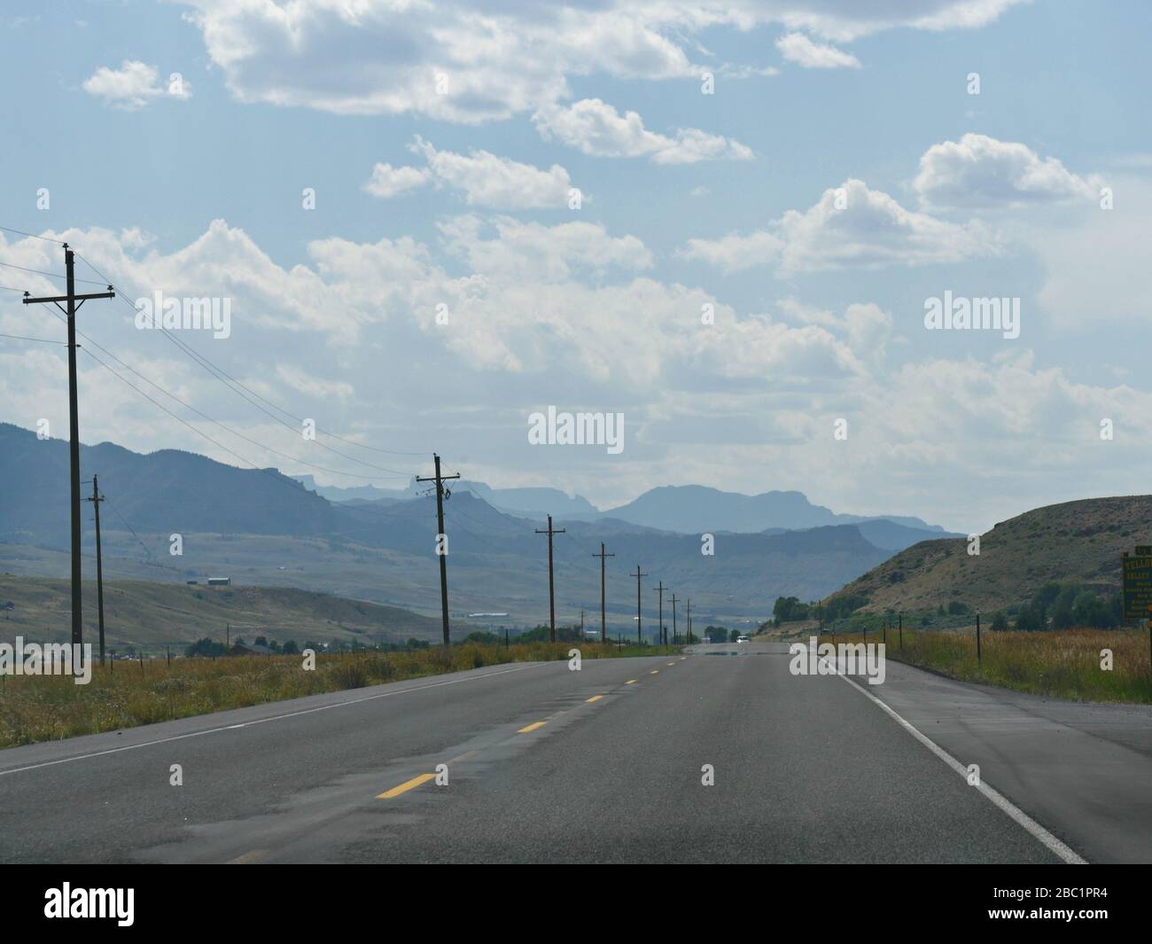 Highway leaving Cody, Wyoming, with mountains in the far distance Stock