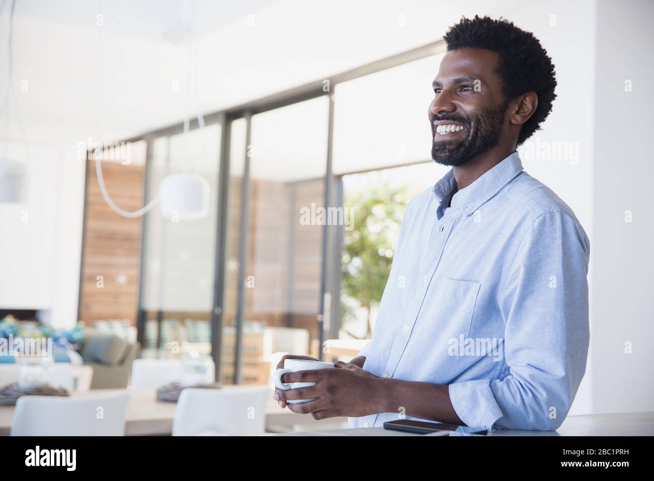 Smiling man drinking coffee, looking away Stock Photo