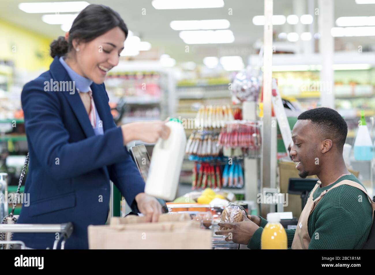 Male cashier helping female customer at checkout in supermarket Stock Photo