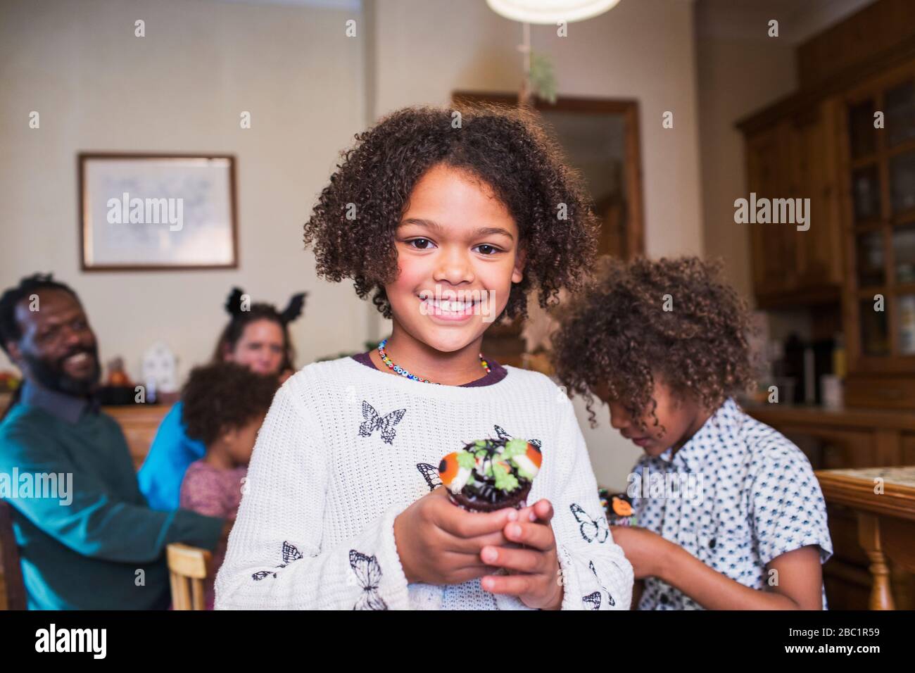 Portrait confident girl holding decorated Halloween cupcake Stock Photo