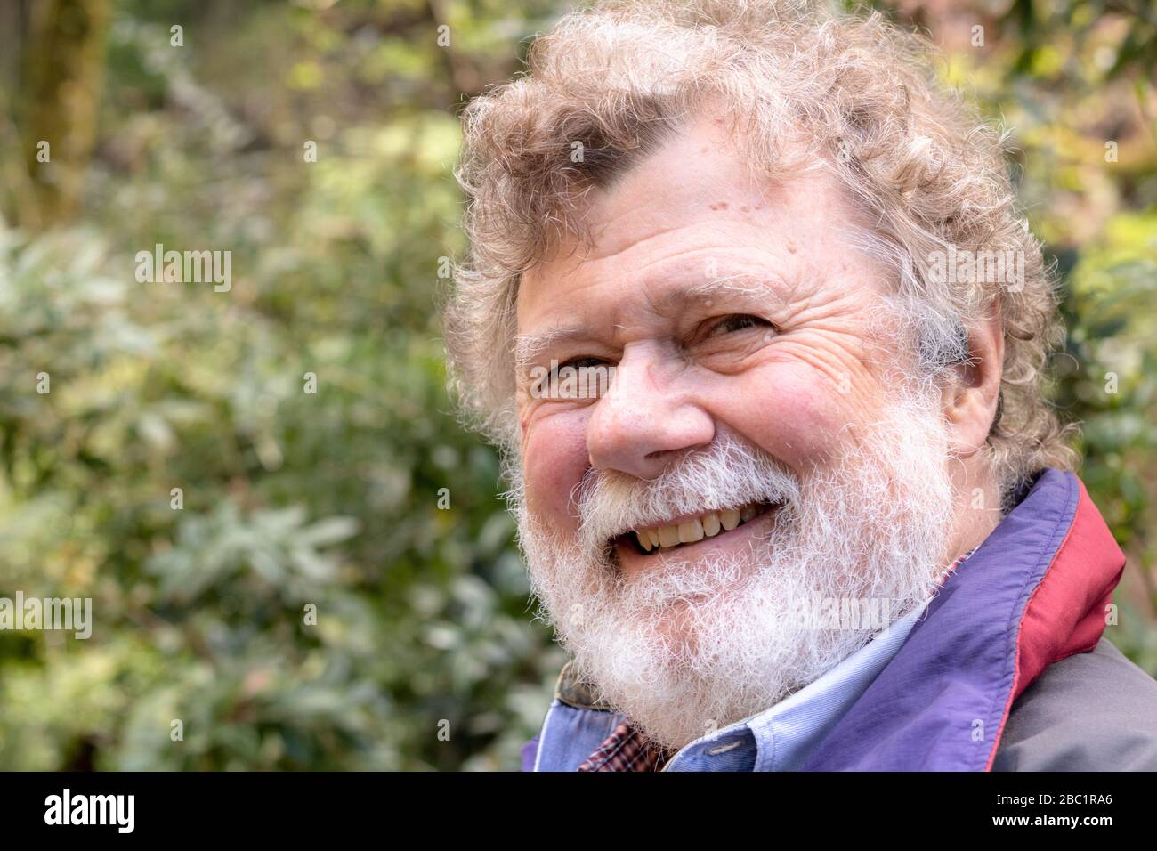 Friendly happy bearded senior male with a twinkle in his eye, a warm, kind healthy confident elderly man outside Stock Photo