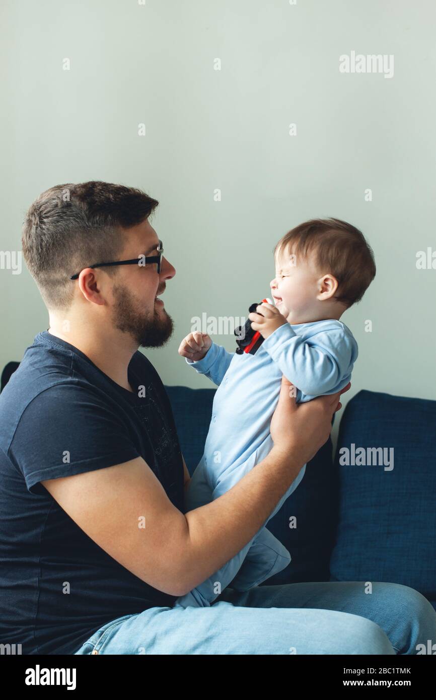 Dad is playing with his son. The baby is laughing. The concept of communication between dads and children, entertainment in quarantine, stay at home. Stock Photo