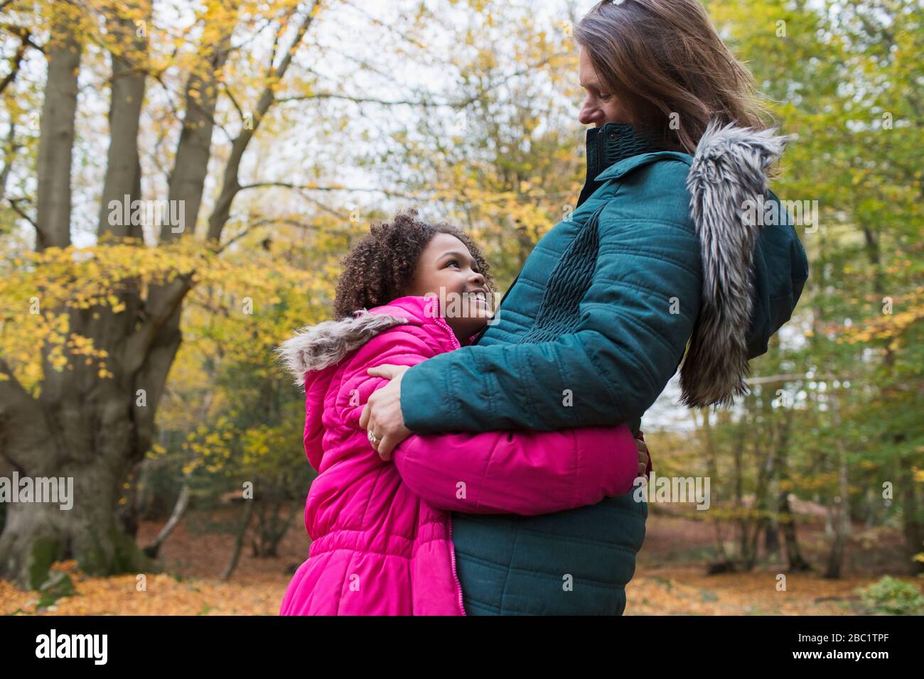 Happy mother and daughter hugging in autumn woods Stock Photo