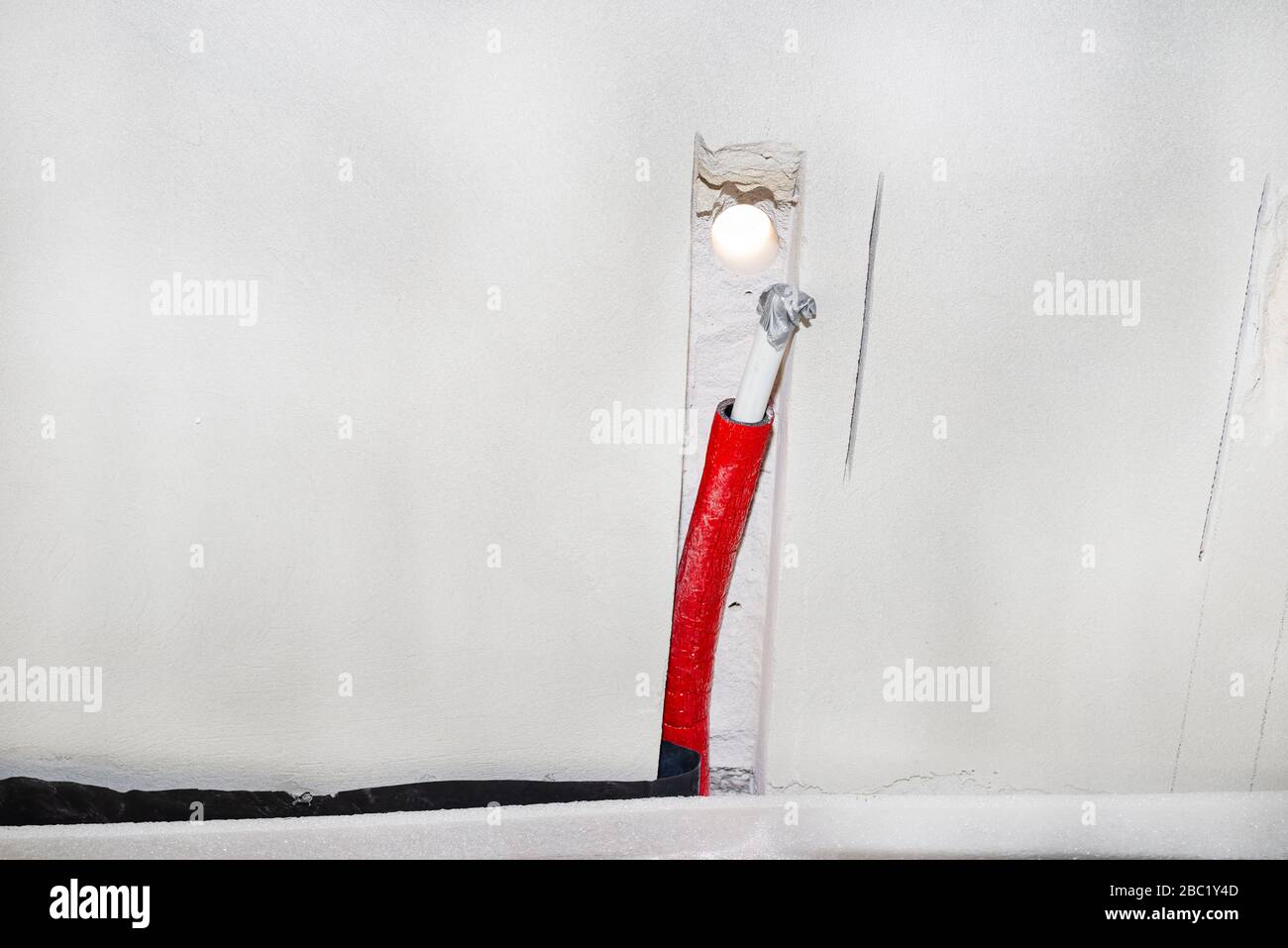 Pipe with cold water coming out of the floor then mounted on the wall, prepared for installing a tap outside the building. Stock Photo